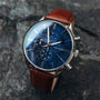 "Naturalist" watch featuring a marble-style blue face with silver accents and a brown leather strap.