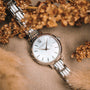 "Skadi" watch featuring a nacre dial and silver bracelet, styled elegantly amidst dried flowers.