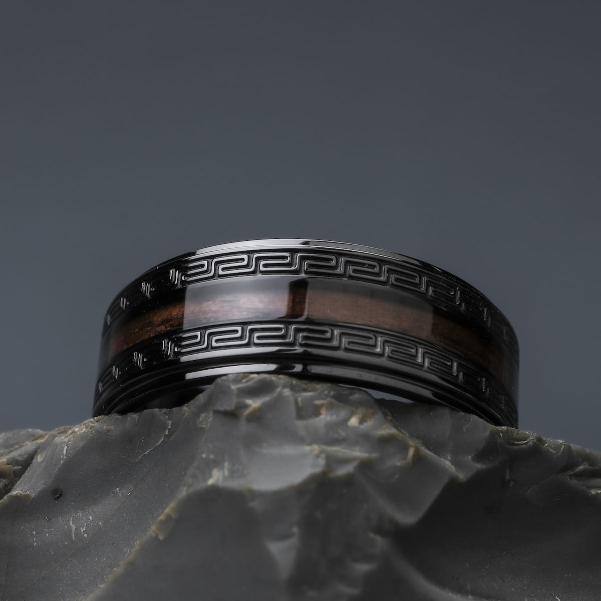"Numerary Ring", a stylish ring featuring walnut and grey design, with intricate dark patterns.