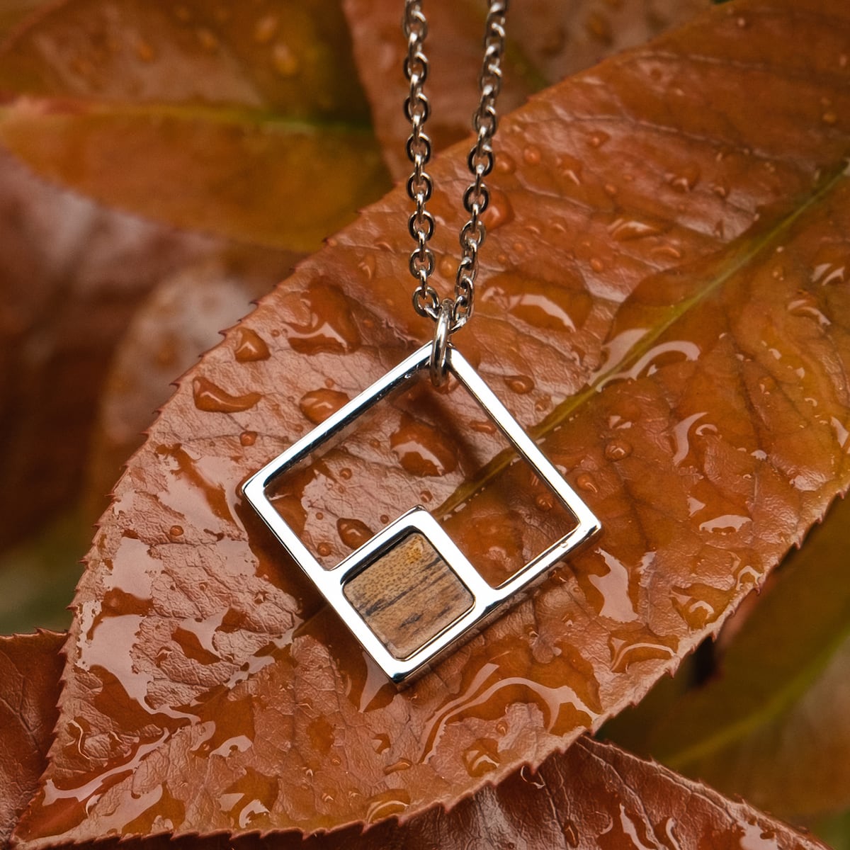 "Geometric Necklace" necklace features a geometric Koa wood and silver design, set against autumn leaves.