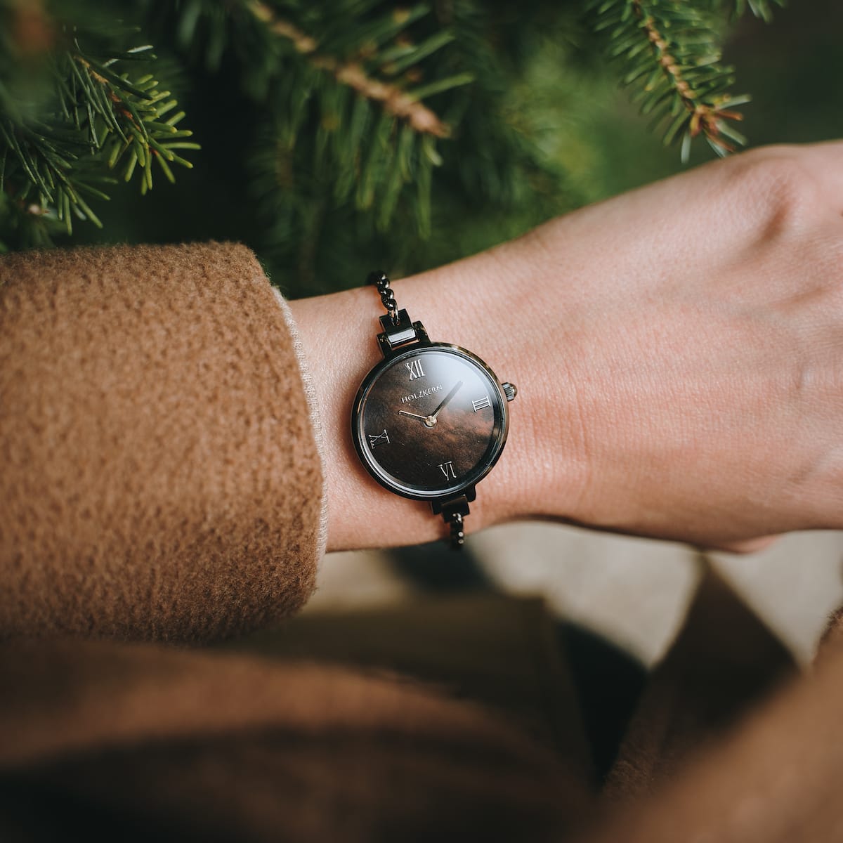"Élisa", an elegant watch with a dark grey face and nacre accents, showcasing a timeless style on a wrist.