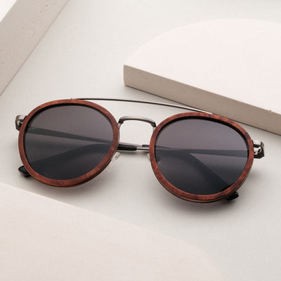 Les lunettes de soleil "The Enchanting" sont dotées d'un design rond avec des accents en noyer et argent antique.