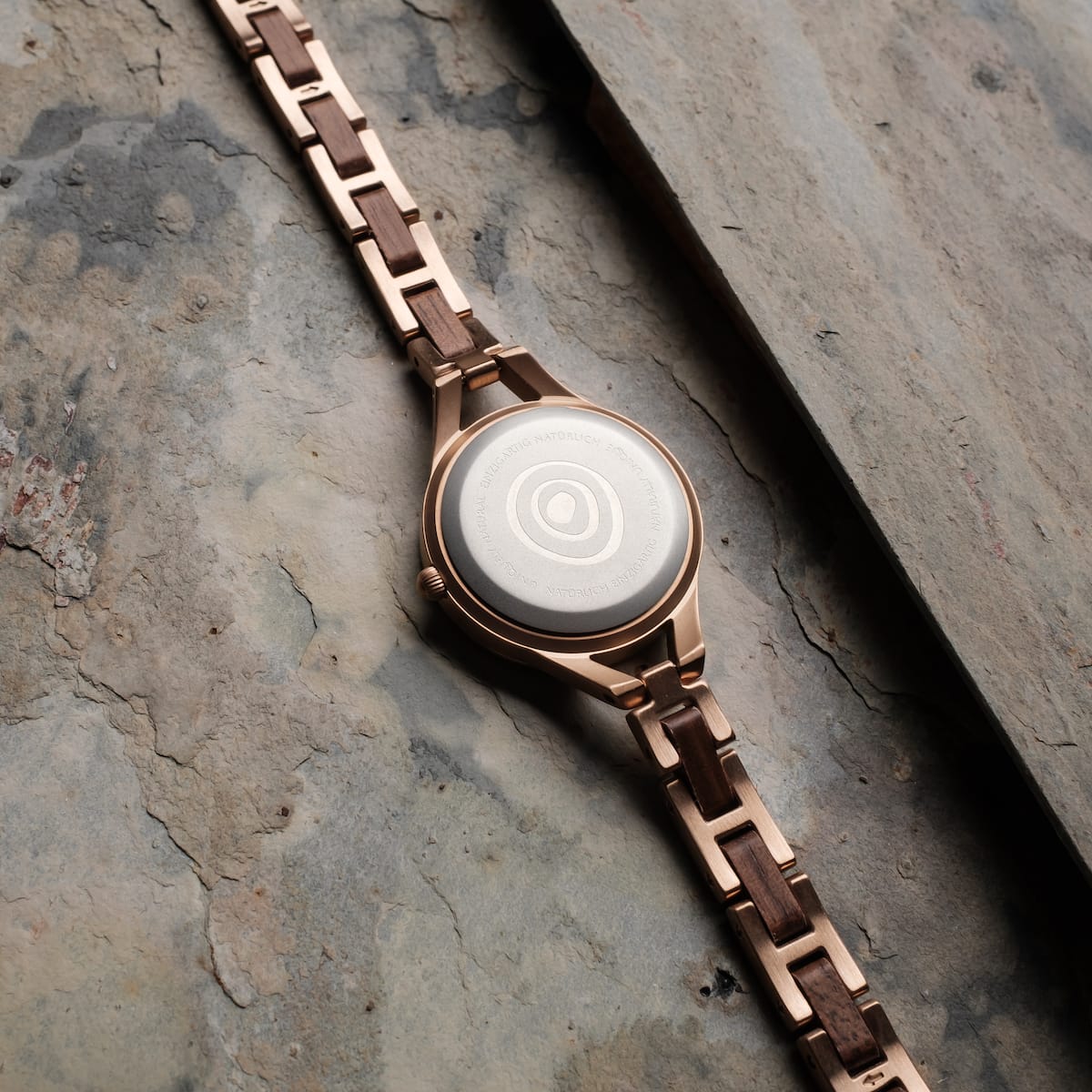 Montre "Fatima" avec des matériaux noyer et nacre avec un design sophistiqué sur une surface texturée.