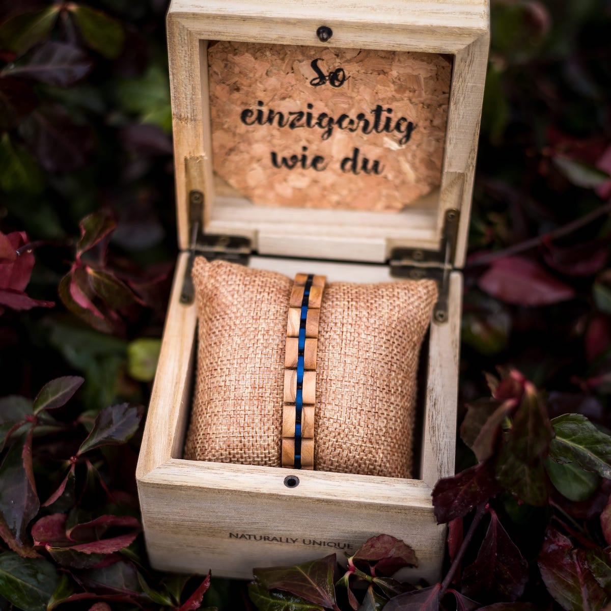 "Fantasia" armbånd, udformet af olivewood og blå accenter, elegant vist i en rustik trækasse.