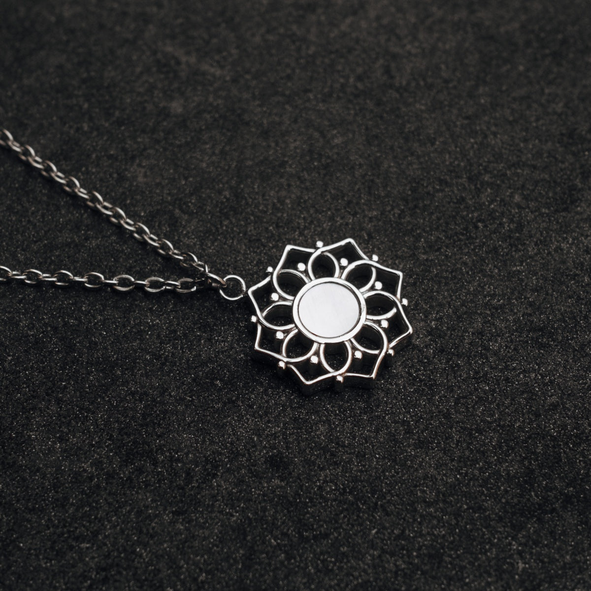 Collier de composition : collier en argent avec nacre blanche, avec un design complexe sur fond sombre.