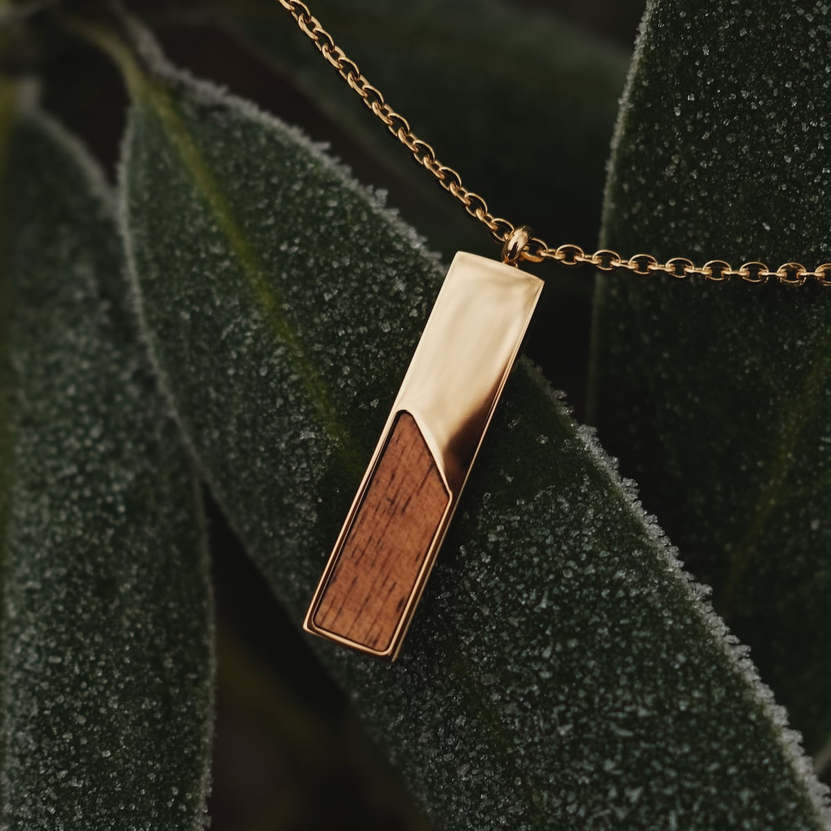 Collar de Ephemera, con un diseño moderno con madera de koa y acentos de oro, en un fondo de hoja textura.