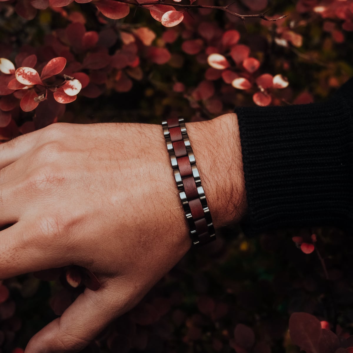 "Triad" bracelet featuring a stylish amaranth and grey design on a wrist amidst autumn foliage.