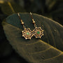 "Aphonia Earrings" - Elegant jade and gold earrings with intricate design on a leafy background.