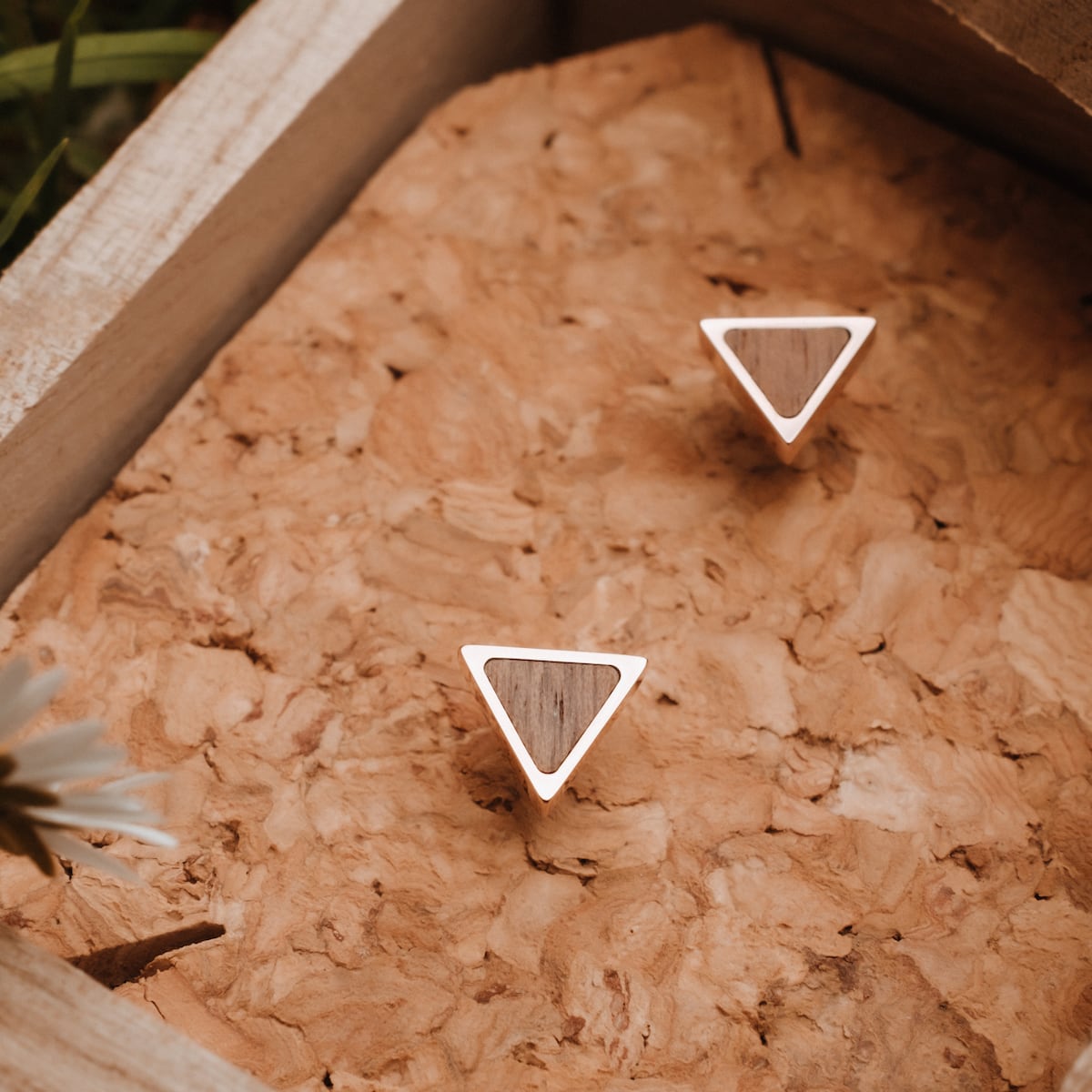 "Scale Earrings" - triangular earrings in Walnut and rose gold, showcasing elegant, modern design on a textured background.