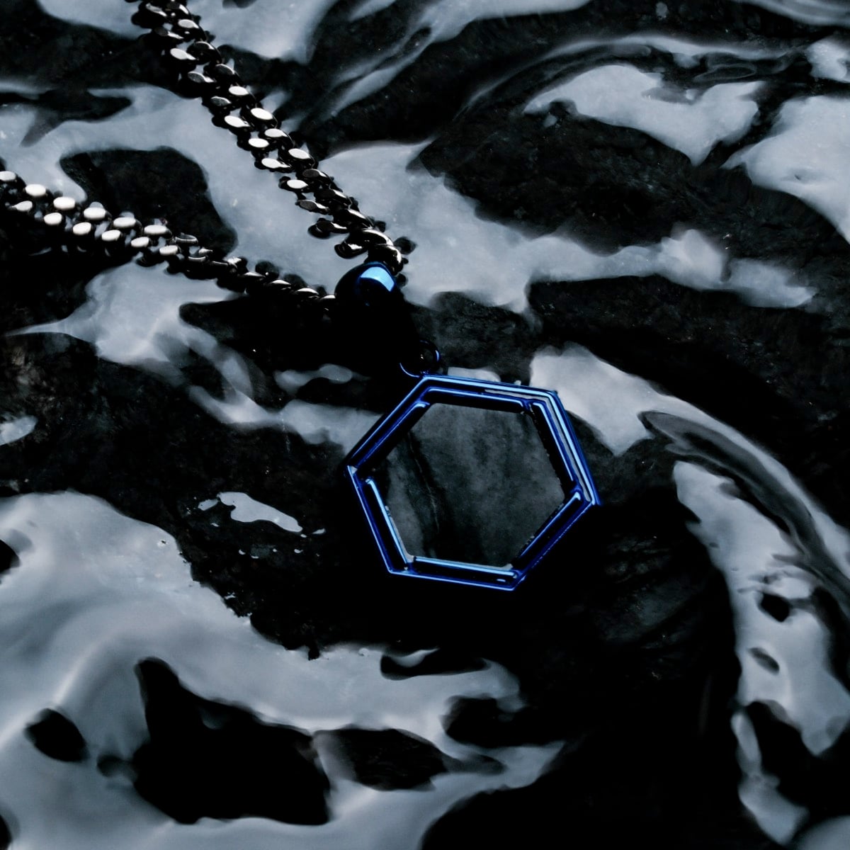 "Axis Necklace" necklace, featuring a geometric design with a sleek, modern style, set against a textured background.