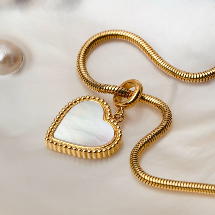 Collier "Amorance Collier" avec pendentif en nacre en forme de cœur et chaîne en or, avec un design élégant et luxueux.