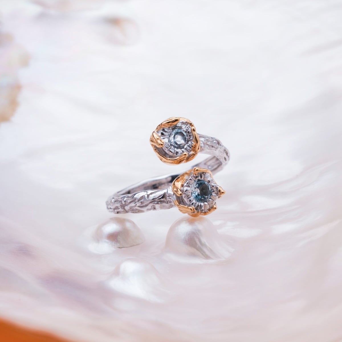 "Silverstream Ring" ring featuring a twisted design in silver and gold with topaz stones, exuding elegance and sophistication.