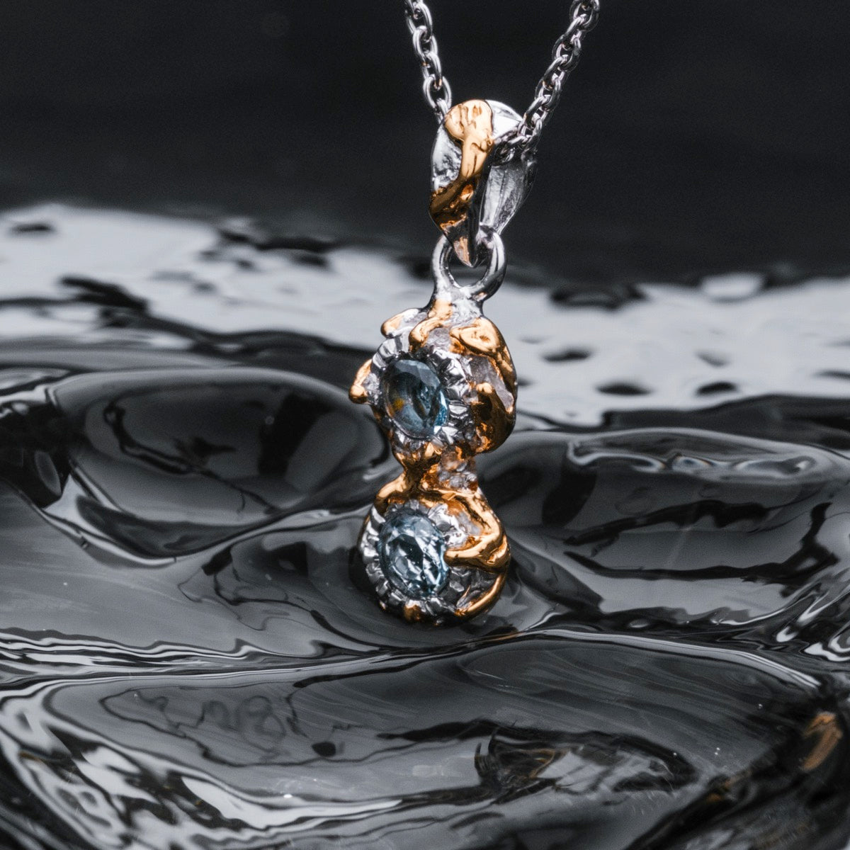 "Silverstream Necklace" necklace featuring topaz and gold accents with an elegant swirling design.