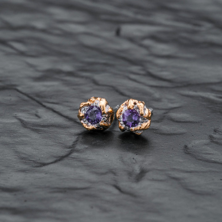 "Silverstream Earrings": Elegant stud earrings featuring amethyst stones in a gold setting, perfect for a sophisticated look.