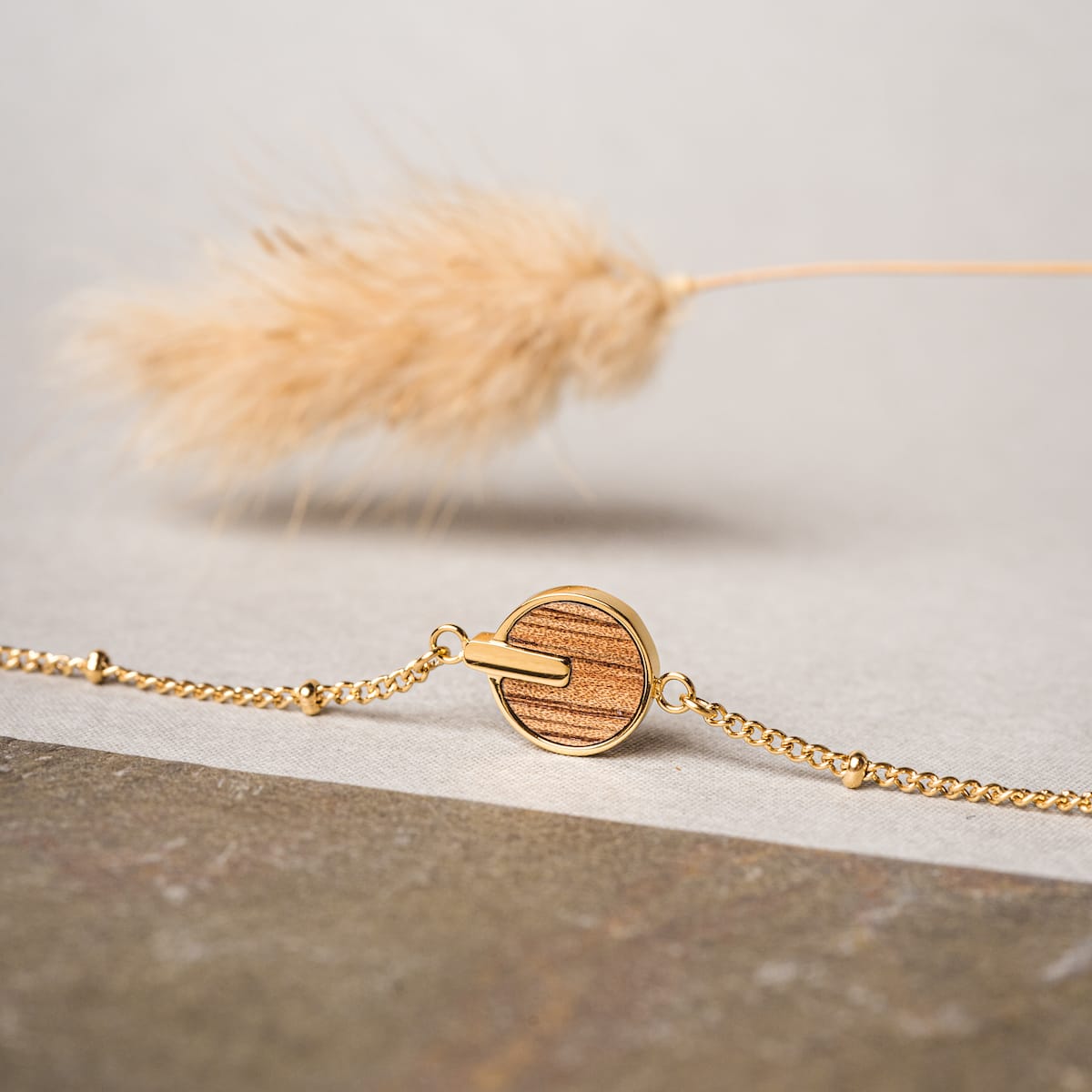 "Opacity Bracelet" bracelet features a marblewood disc and gold chain for an elegant look.