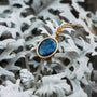 Collar espejo en oro, con un colgante lazuli lapis engastado contra un fondo blanco texturado.