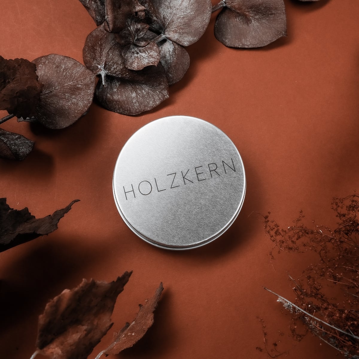 "Wood Care Balm 30ml", wood care balm in a sleek metal tin, styled with autumn leaves on a warm brown background.