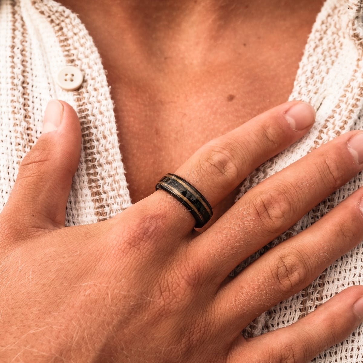 "Cartesian Ring", a stylish ring crafted from zebrawood and black material, worn on a hand with a textured fabric background.