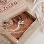 "Awakening Necklace" necklace, featuring nacre and rose gold, elegantly displayed in a rustic wooden box.