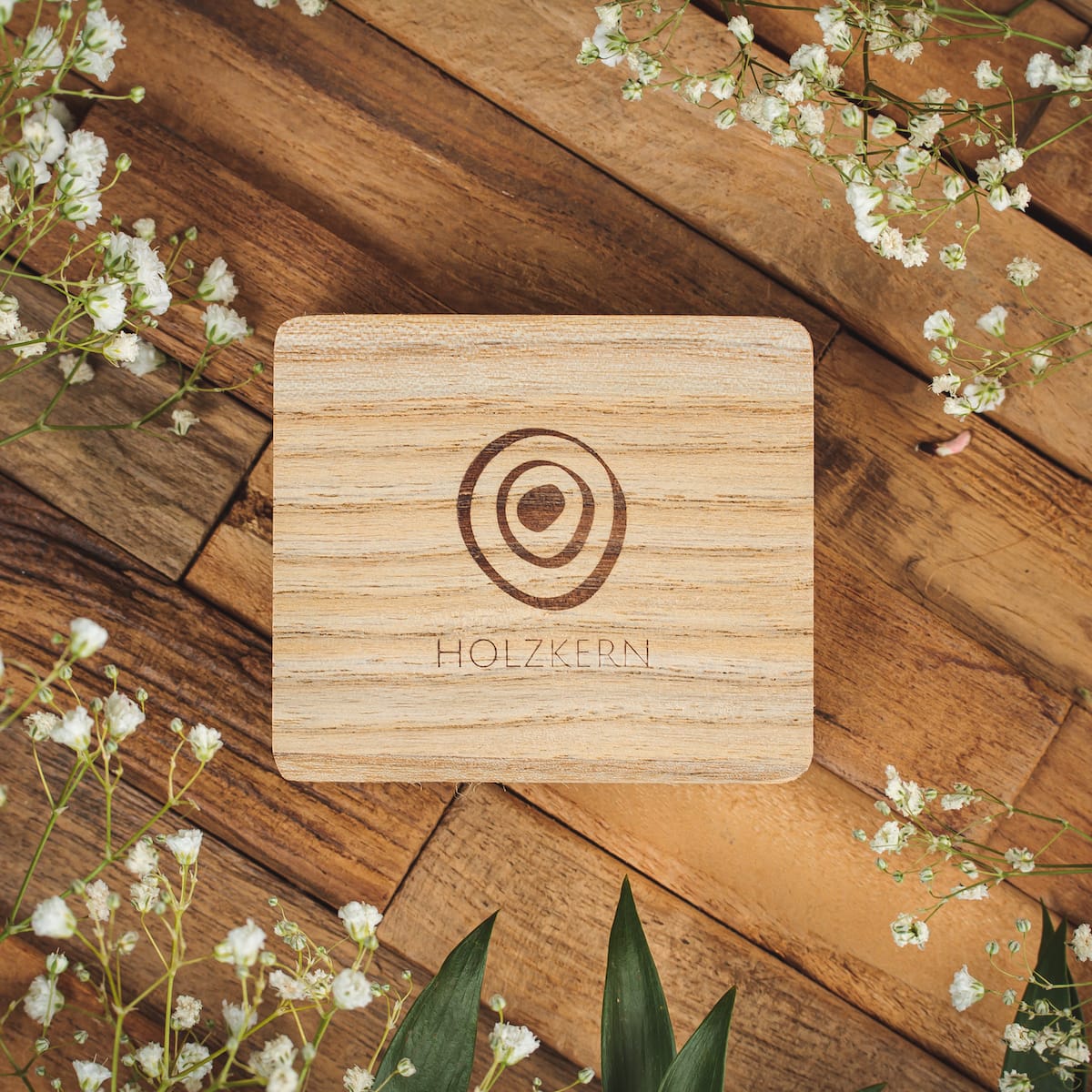 "Biżuteria Single- Box" drewniane pudełko biżuterii z naturalnym i eleganckim designem, otoczony delikatnymi białymi kwiatami.