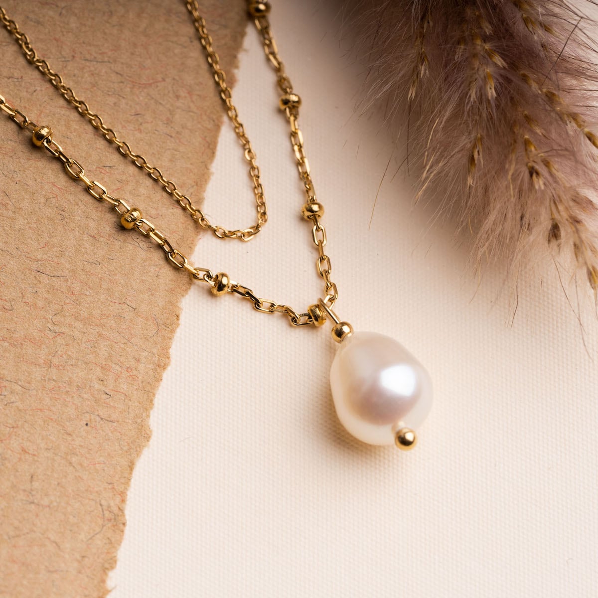 "Panoramic Necklace", a gold necklace with a white pearl pendant, showcasing an elegant and timeless style.