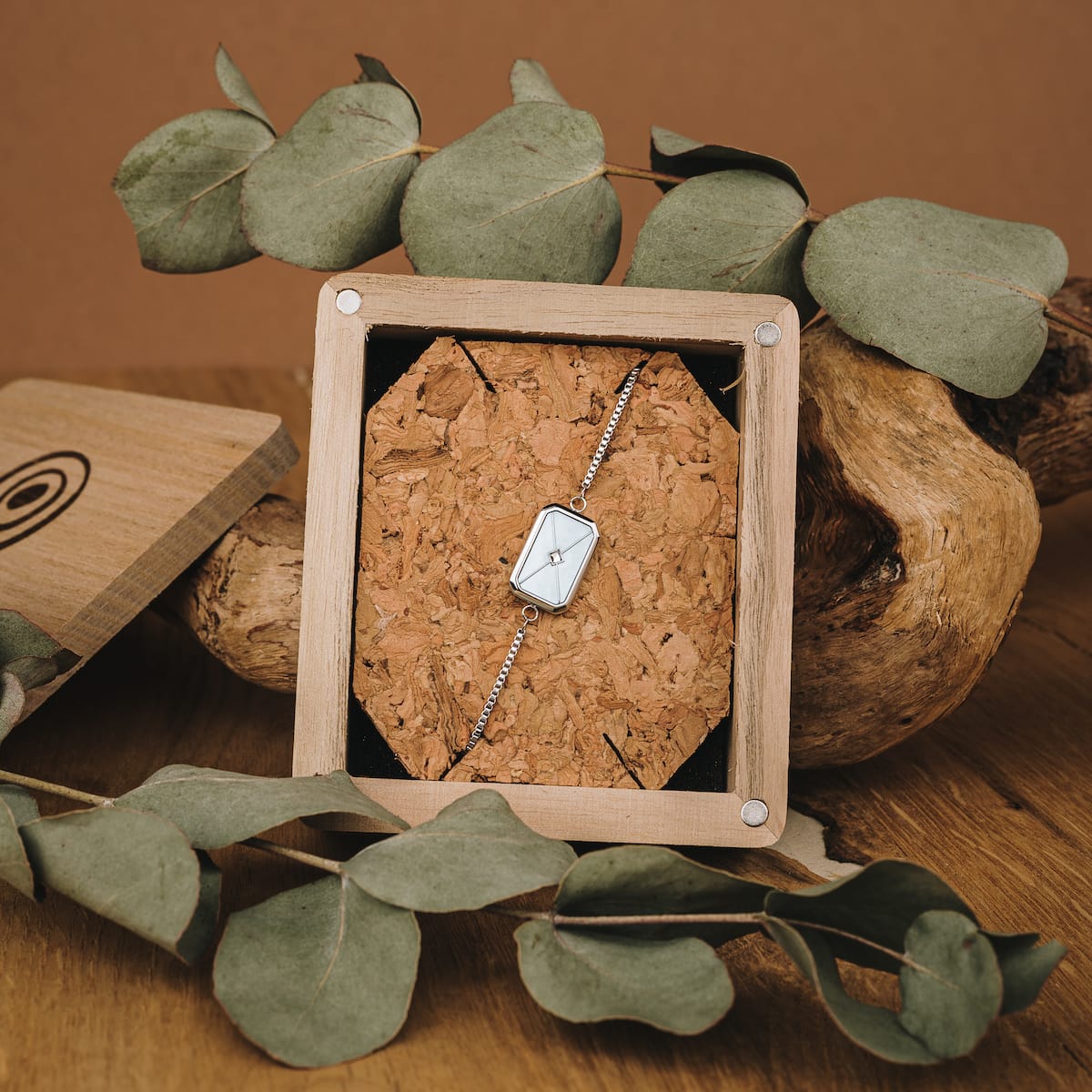 "Aquarell Bracelet" bracelet featuring a sleek design with white nacre and silver accents in a rustic wooden display.