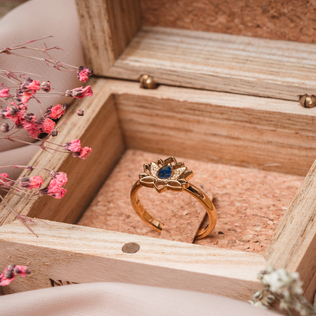 "Balance Ring": Elegant gold ring with lapis lazuli, featuring a floral design in a wooden box.