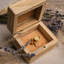 "Pixa Ring", a stylish gold ring with pink nacre, elegantly displayed in a wooden box with lavender accents.