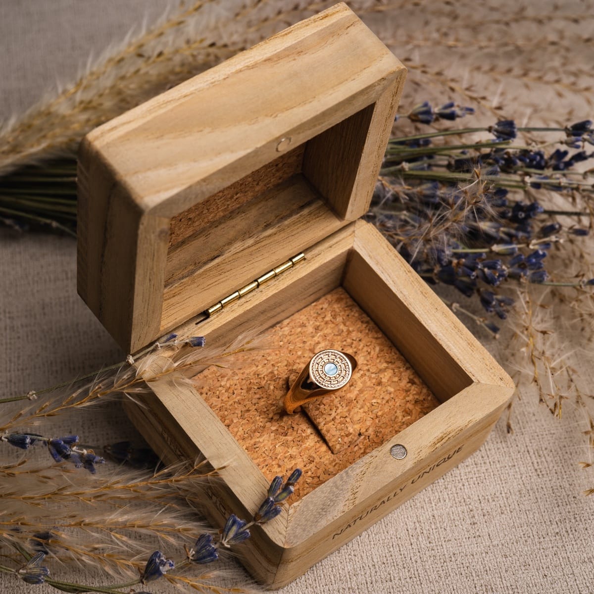 "Pixa Ring" ring in rose gold with nacre detail, presented in a rustic wooden box with a vintage aesthetic.