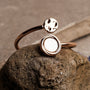 "Zendala Ring", un anneau élégant avec nacre et or rose dans un design minimaliste, exposé sur une surface en pierre.