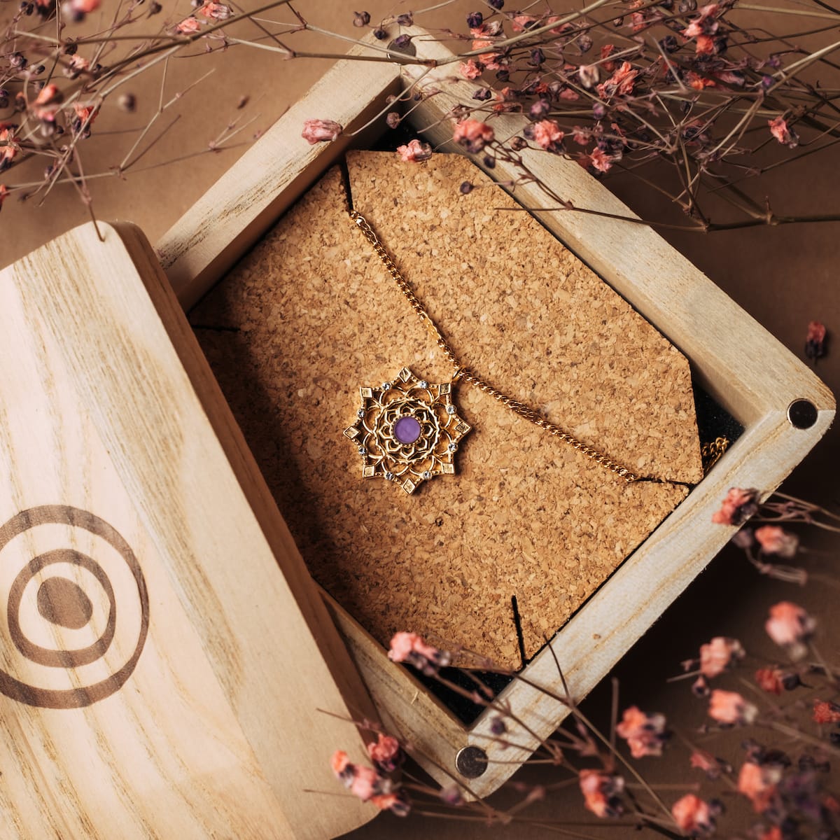 "Aphonia Necklace" necklace, featuring an intricate gold design with an amethyst centerpiece, elegantly displayed in a wooden box.