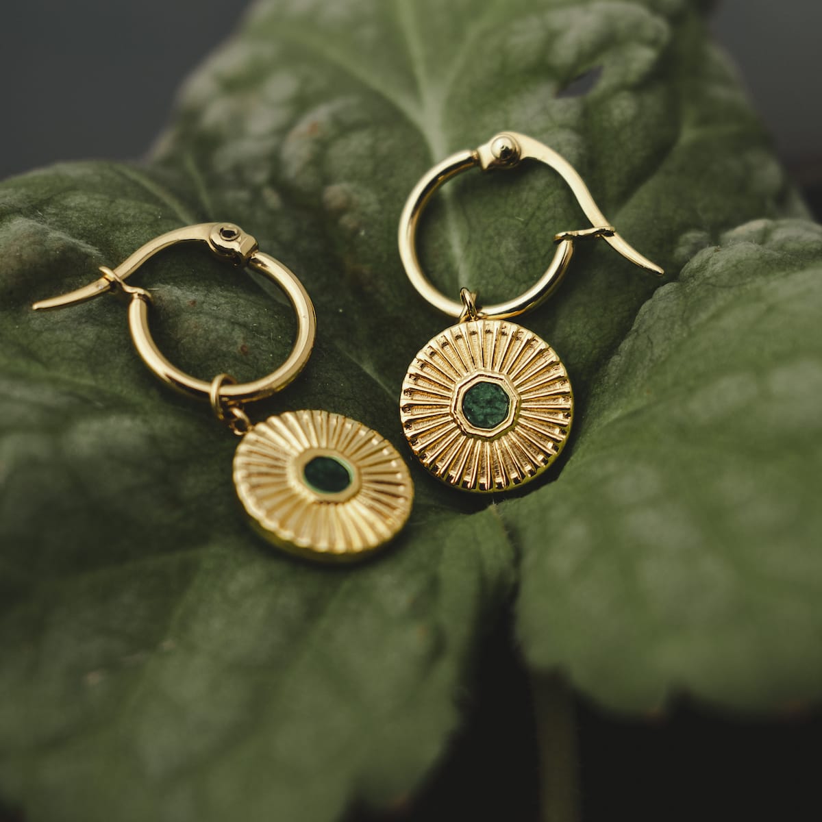"Stencil Earrings", elegant earrings with a marble and gold design showcased on a leaf background.
