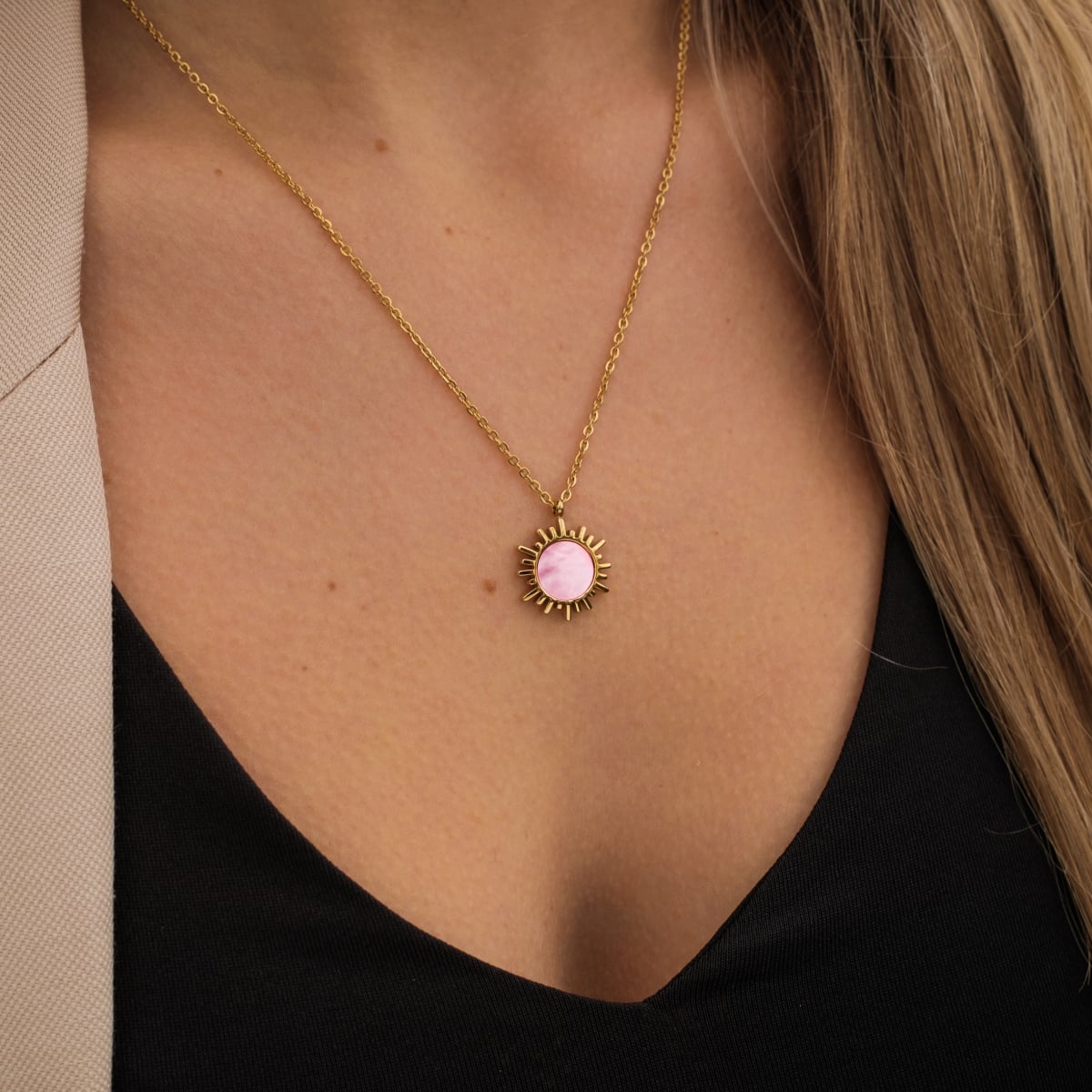 "Shade Necklace" necklace featuring a pink nacre pendant with a gold sunburst design.