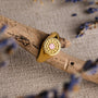 "Pixa Ring" ring with a pink nacre and gold design, set against a natural wood backdrop.