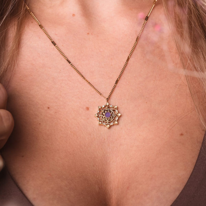 "Aphonia Necklace", an elegant necklace featuring a gold chain with an intricate amethyst pendant.