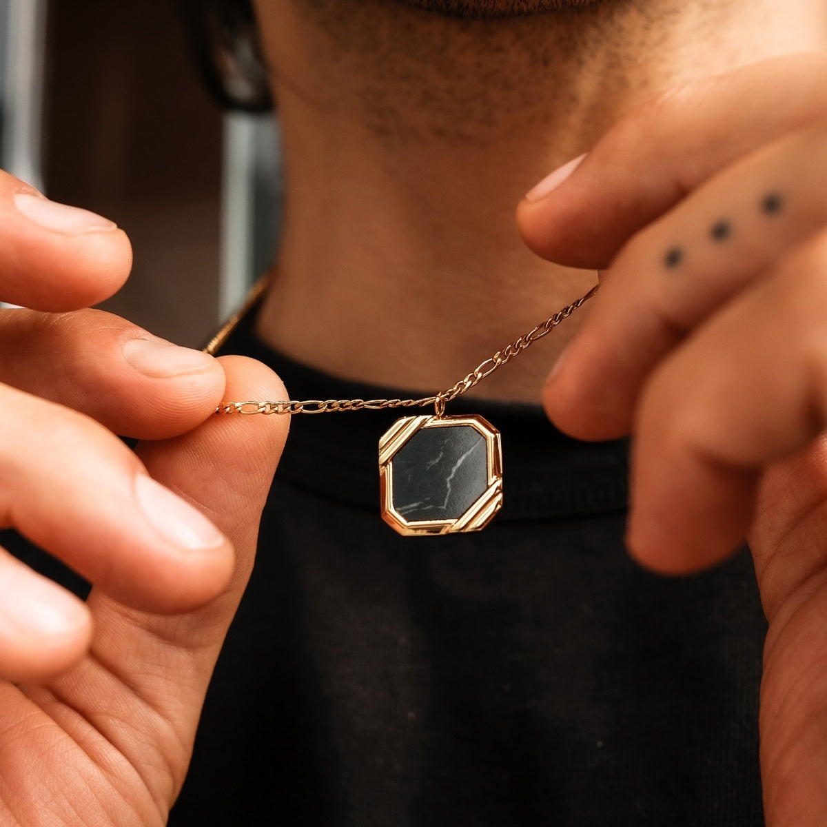 "Scalar Ketting" ketting heeft een marmeren ontwerp met een gouden ketting in een stijlvolle, geometrische tegenhanger.
