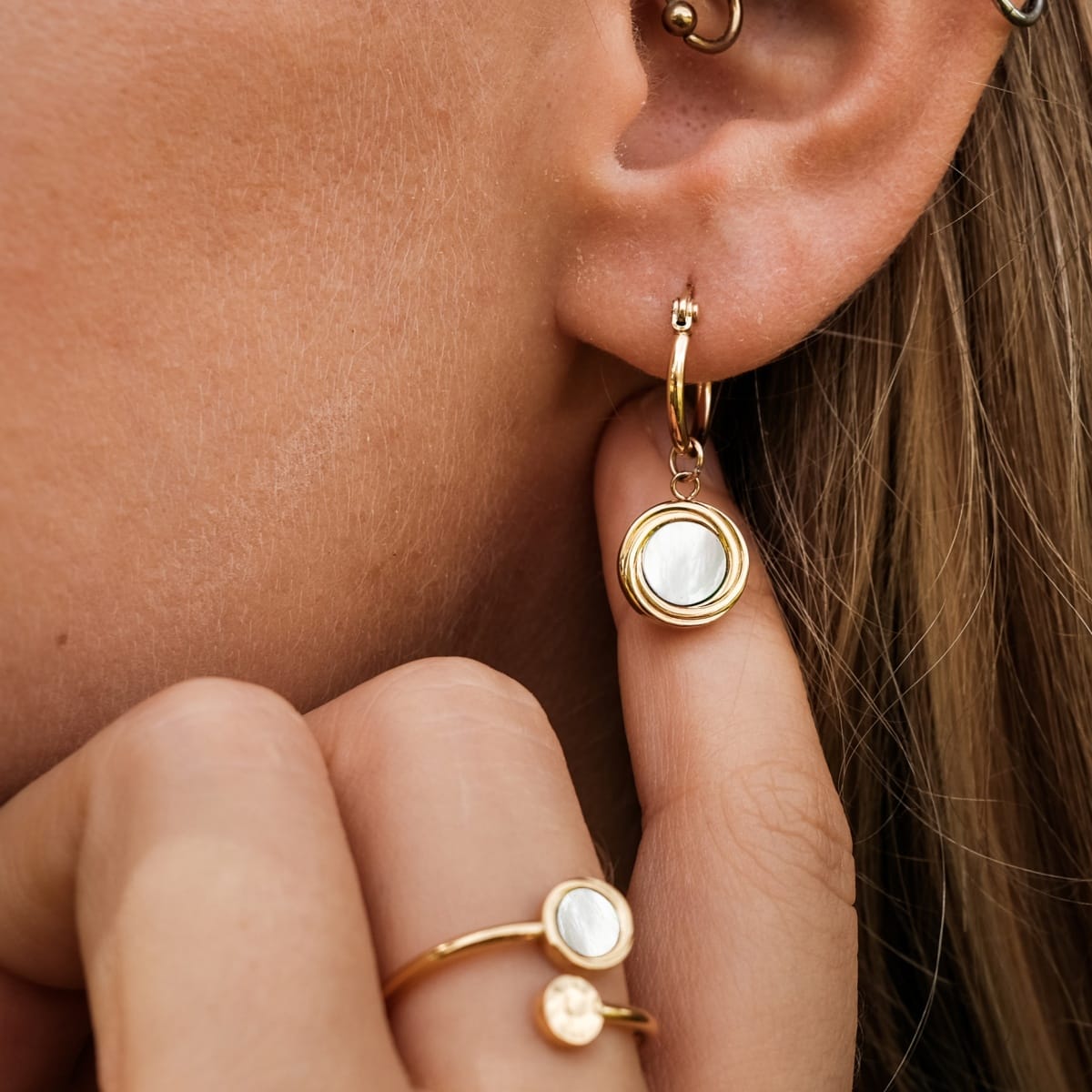 "Zendala Earrings": elegant gold hoop earrings with white nacre accents.