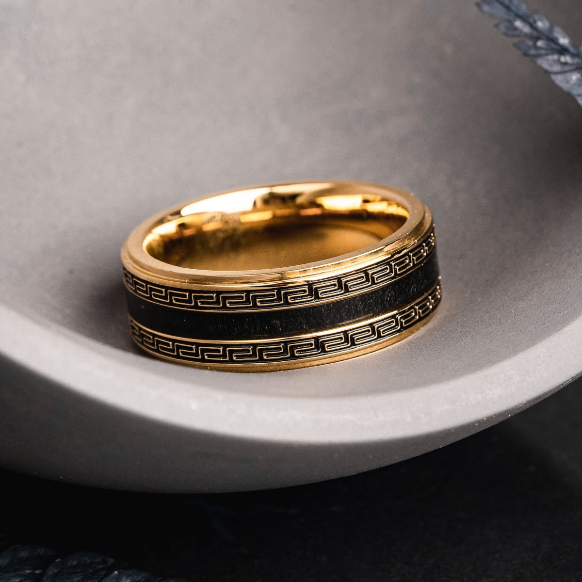 "Numerary Ring", a stylish gold ring with intricate black detailing, displayed elegantly.