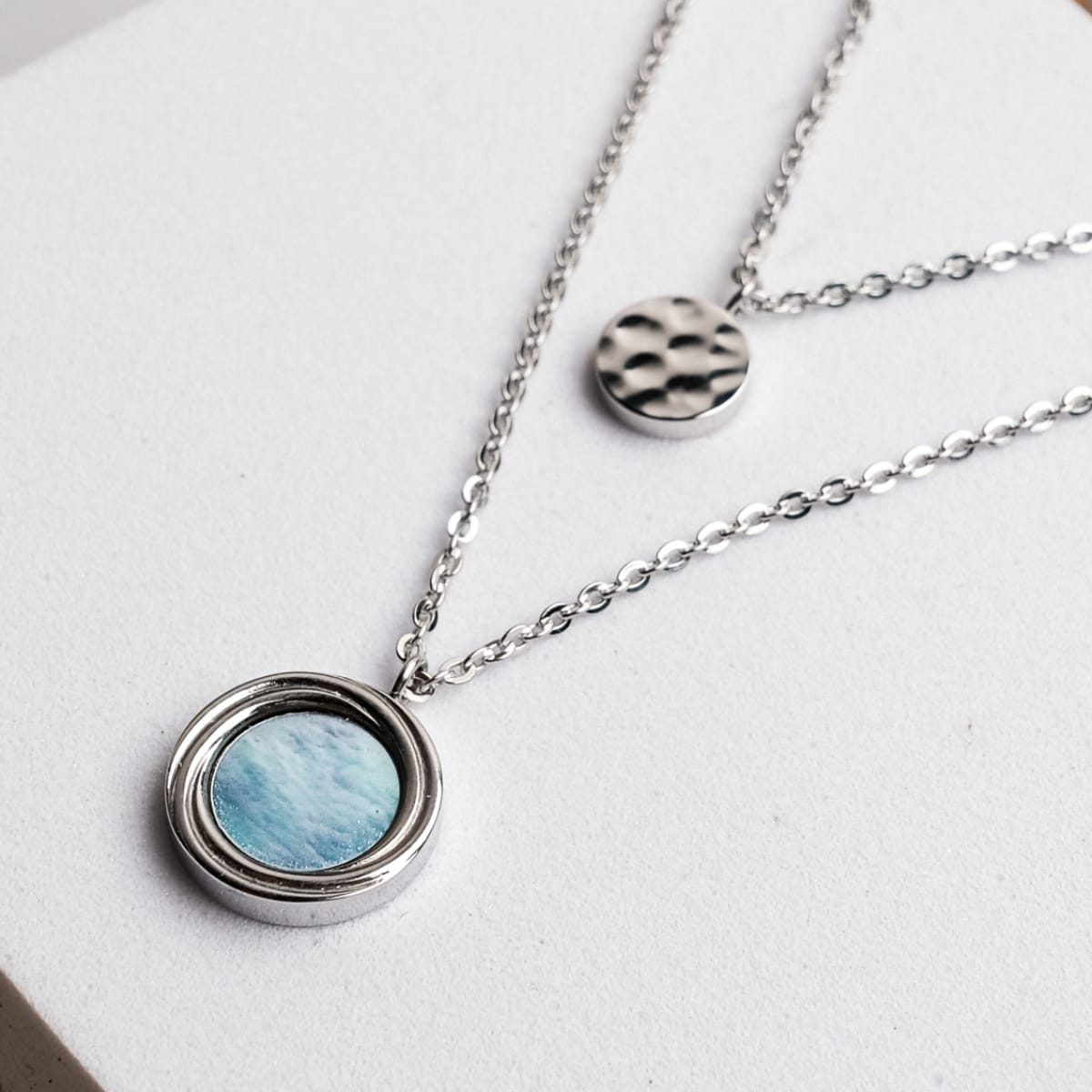 "Zendala Necklace", a stylish necklace featuring a blue nacre and silver design, perfect for an elegant look.