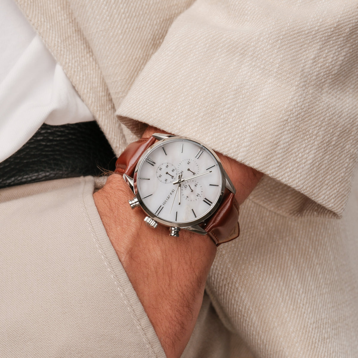 "Melodieus" horloge met een marmeren wijzerplaat met zilveren accenten en een bruine leren band, gedragen aan de pols.