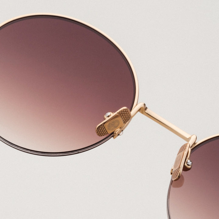 "The Adventurous" sunglasses feature a stylish walnut and gold design with round lenses.