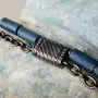"Supersonic" bracelet with a sleek maple and gray design and metallic accents on a stone background.