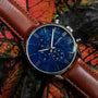 "Naturalist", elegant watch with a blue marble face and silver accents, complemented by a brown leather strap.