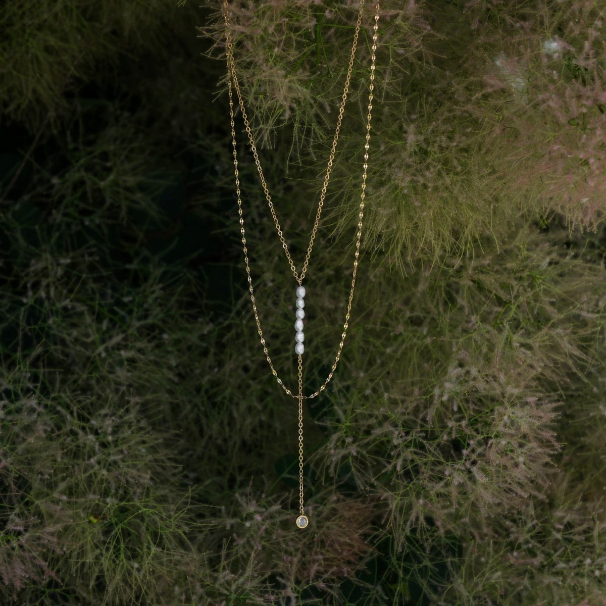 "Summersweet Necklace" necklace featuring a delicate pearl and zirconia design, set against a natural backdrop for an elegant appearance.