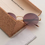 "The Adventurous" sunglasses with a walnut and gold design, featuring round lenses and a cork case for a unique style.