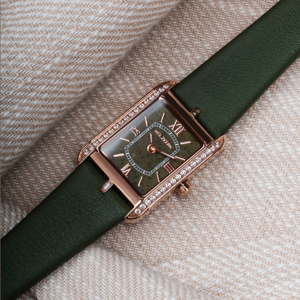 "Memoire" watch with a green leather strap and an elegant rectangular face adorned with crystals.