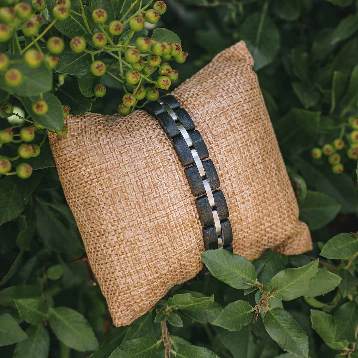 "Fantasia" bracelet featuring a modern maple and silver design, displayed on a textured cushion amidst greenery.