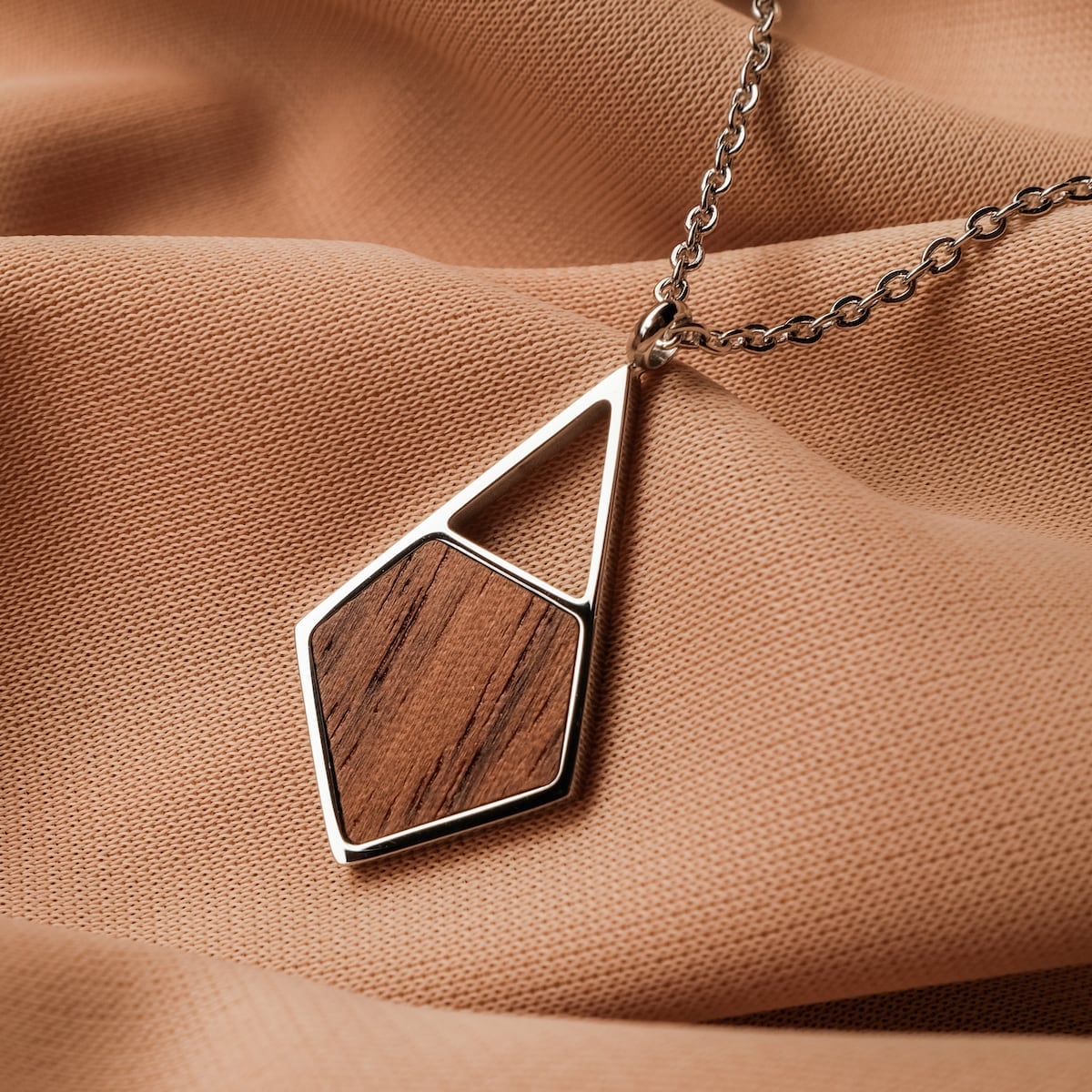 "Mandala Necklace" featuring a geometric walnut and silver design on a sleek pendant necklace.