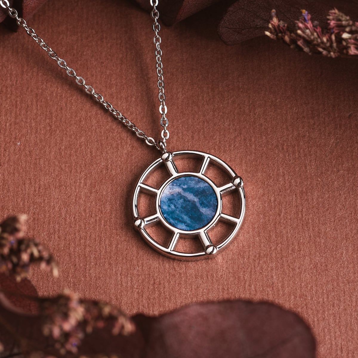 "Amulet Necklace" features a round marble pendant encased in a silver frame with a delicate chain.